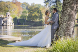 couple de jeunes mariés adossés à un arbre du parc majolan à Blanquefort superbe robe blanche de mariée avec une longue traine en Gironde sous l'oeil du photographe de mariage à Bordeaux Sébastien Huruguen